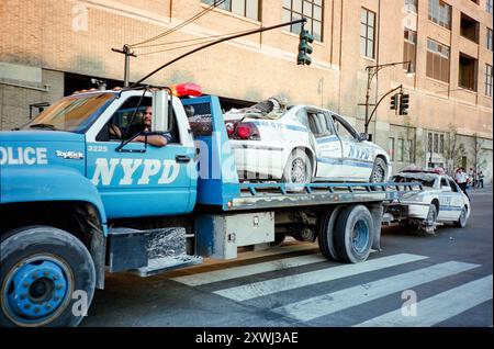 11 septembre 2001 NYC - le NYPD remorque des voitures du NYPD détruites lors de l'attaque sur la Westside Highway. Le 11 septembre 2001, quatre avions commerciaux américains ont été détournés par Al-Qaïda, un groupe terroriste islamiste extrémiste, et ont été armés contre les États-Unis. Tuant près de 3000 personnes et en blessant 6000 autres, ce fut la pire attaque qui ait eu lieu sur le sol des États-Unis. Deux des avions ont été transportés dans le World Trade Center de New York, détruisant les tours jumelles et tuant 2 977 personnes. Ce sont des photos de ce jour et de la semaine à suivre et tournées sur film Banque D'Images