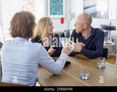 Symbolfoto zum Thema Beratung. Eine Junge Frau und ein Junger Mann sitzen zu Hause zusammen an einem Tisch und werden beraten. Berlin, 13.08.2024. Ber Banque D'Images