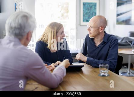 Symbolfoto zum Thema Beratung. Eine Junge Frau und ein Junger Mann sitzen zu Hause zusammen an einem Tisch und werden beraten. Berlin, 13.08.2024. Ber Banque D'Images