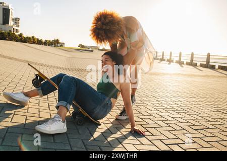 Jeunes femmes animées profitant d'un moment amusant à l'extérieur pendant une pause de l'université, montrant la joie et l'amitié des meilleures amies passant du temps ensemble. Banque D'Images