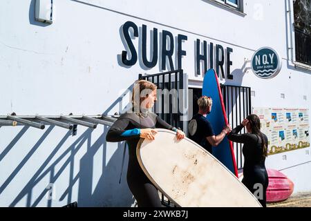 Les vacanciers retournent leurs planches de surf louées au NQY Surf Schoo,l au GT Great Western à Newquay en Cornouailles au Royaume-Uni. Banque D'Images