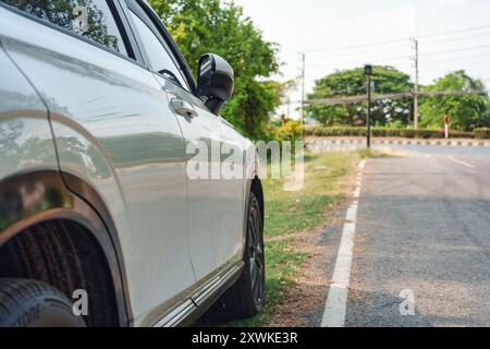 Vue latérale d'une voiture SUV moderne blanche avec asphalte taché garé sur le bord de la route Banque D'Images