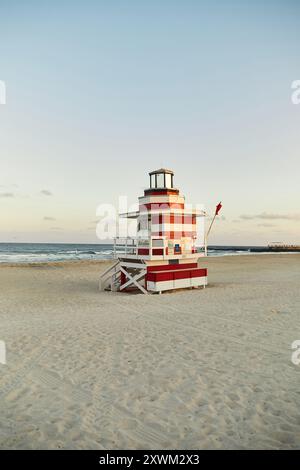 Un stand de sauveteur rouge et blanc se dresse sur une plage de sable à Miami, en Floride. Banque D'Images