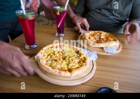 Délicieuses pizzas et boissons rafraîchissantes partagées entre amis - la recette parfaite pour une soirée amusante! Banque D'Images