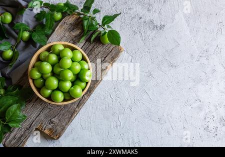 Prunes vertes biologiques fraîches mûres ou greengage dans un bol sur fond rustique blanc, tas de concept de fruits d'été Banque D'Images