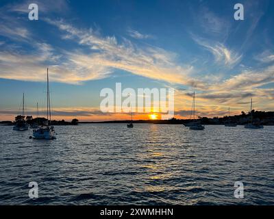 Yachts amarrés sur des bouées près du rivage dans la baie d'Uvala Gradina près de la ville de Vela Luka sur l'île de Korcula aux lumières du coucher du soleil en Croatie Banque D'Images