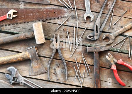 Ancien outil à main sur une surface en bois. Clé réglable, clé, hache, marteaux, clous et pinces. Outils de réparation et de construction, vue de dessus Banque D'Images