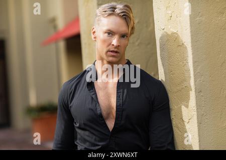 Un bel homme blond en tenue élégante pose contre un mur à Orlando, en Floride. Banque D'Images