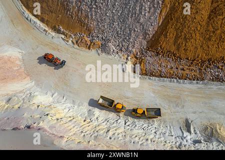 Vue aérienne par drone de machines de construction, dumprer et transporteur dans une fosse de sable, chargement de ressources naturelles Banque D'Images