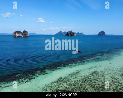 Vue aérienne de la plage de Ko Ngai avec son incroyable récif corallien et ses eaux turquoise et d'autres îles Trang en arrière-plan Banque D'Images