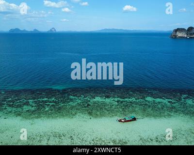 Vue aérienne de Ko Ngai à marée haute avec un bateau à longue queue au-dessus de l'eau turquoise et l'île de Ko Maa en arrière-plan Banque D'Images