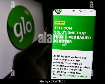 Personne tenant le téléphone portable avec la page Web de la société de télécommunications nigériane Globacom Limited (GLO) avec le logo. Concentrez-vous sur le centre de l'écran du téléphone. Banque D'Images