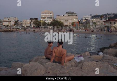 Les gens sont assis sur un brise-lames rocheux à la plage de Bat Galim le 14 août 2024 à Haïfa, Israël. Banque D'Images