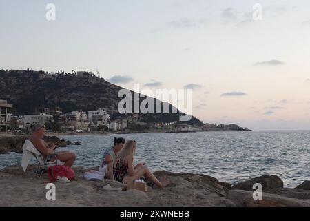 Les gens sont assis sur un brise-lames rocheux à la plage de Bat Galim le 14 août 2024 à Haïfa, Israël. Banque D'Images