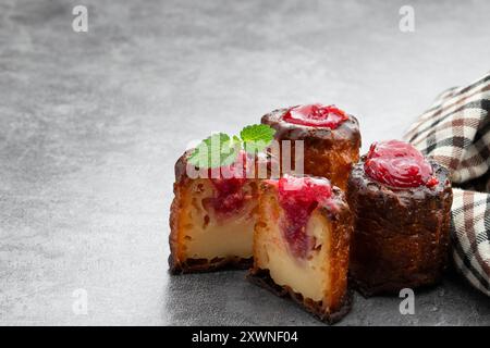 Canelé avec confiture de framboises sur fond gris Banque D'Images