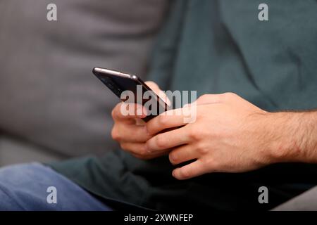 les mains d'un jeune homme tenant un téléphone portable Banque D'Images