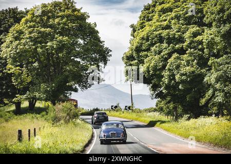 Une voiture classique passe devant des cottages pittoresques sur une route paisible dans la pittoresque campagne écossaise Banque D'Images