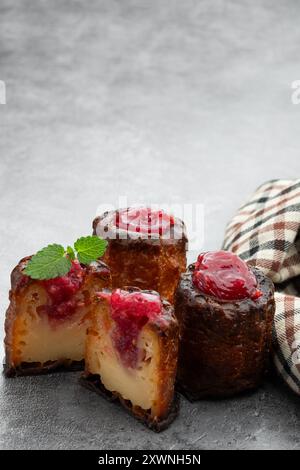 Canelé avec confiture de framboises sur fond gris Banque D'Images