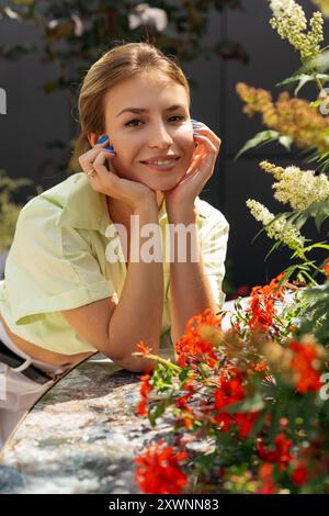 Portrait d'une femme heureuse souriante debout dans un jardin appuyé sur une table Banque D'Images