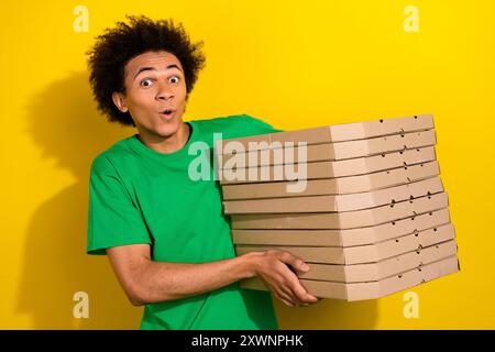 Photo du gars impressionné de bonne humeur porter un t-shirt vert commandant pizza emtpy espace isolé fond de couleur jaune Banque D'Images