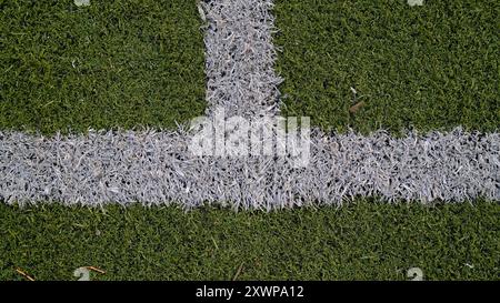 Intersection des lignes de démarcation blanches sur gazon artificiel vert. Détail des marquages de football ou de terrain de football. Géométrie du terrain de sport. Banque D'Images