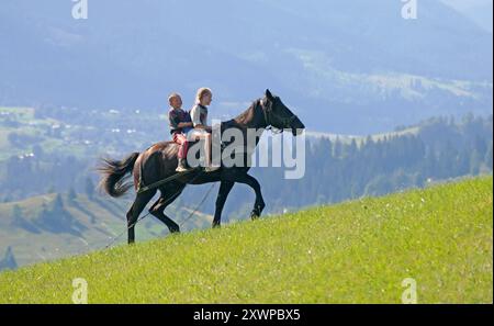 RÉGION DE TCHERNIVTSI, UKRAINE - 31 JUILLET 2024 - des enfants montent à cheval dans les Carpates, district de Vyzhnytsia, région de Tchernivtsi, ouest de l'Ukraine. Banque D'Images