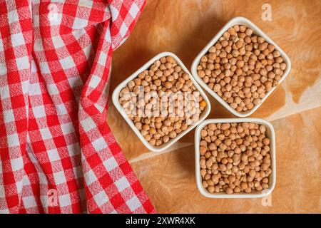 Trois bols de pois chiches avec un tissu à carreaux rouge sur la table, vue de dessus Banque D'Images