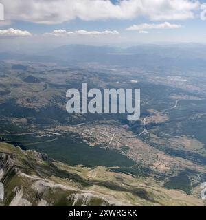 Paysage urbain aérien, depuis un planeur, avec le village historique d'Assergi et le carrefour de l'autoroute à proximité, tourné du nord dans la lumière de l'été, Apennin Banque D'Images