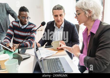 Groupe diversifié de professionnels d'affaires collaborant dans la réunion de bureau. Équipe multiculturelle utilisant des ordinateurs portables et un microphone pour la présentation. Concept de Banque D'Images