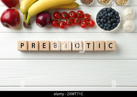 Mot prébiotique fait de cubes et de différents produits sur table en bois blanc, pose à plat. Espace pour le texte Banque D'Images