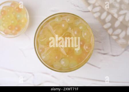 Savoureux thé mousseux en verre et perles de tapioca sur table blanche, vue de dessus Banque D'Images