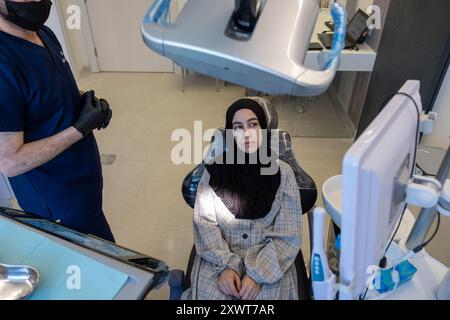 Conversation entre un dentiste et une femme musulmane portant le hijab regardant ses dents radiographie à l'écran et le médecin décrit son traitement Banque D'Images