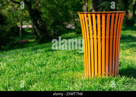 Poubelle dans un parc verdoyant. Une poubelle colorée dans l'herbe. Concept de propreté dans la ville, un geste de civisme et de respect Banque D'Images