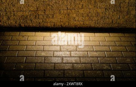 Plancher de chaussée éclairé par l'éclairage de rue : motif et texture - lumière et ombre. Lueur dorée. Banque D'Images