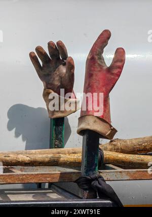 Paire de gants rouges de travailleur en caoutchouc sale : environnement de service public isolé sur fond blanc - lumière et ombre. Banque D'Images