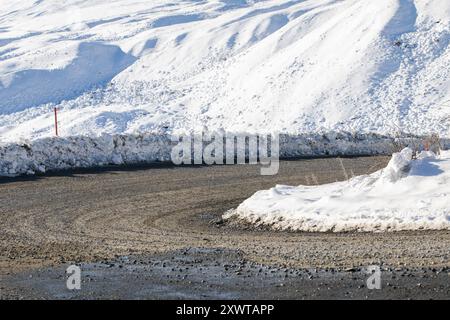 Une route sinueuse enneigée serpente à travers un paysage hivernal pittoresque, invitant à l'exploration Banque D'Images