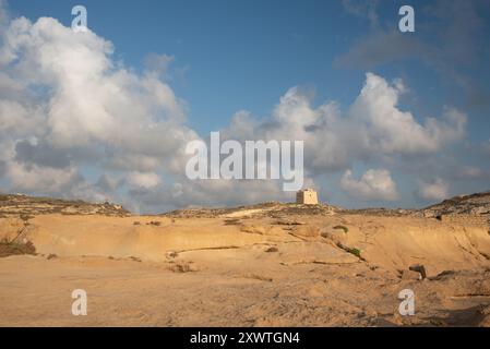 Paysage rocheux contre un ciel bleu avec des nuages. Une petite tour ancienne se dresse à l'horizon. Banque D'Images