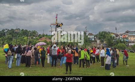 Balikpapan, Indonésie - 18 août 2024. La grimpeuse est encouragée par la foule pendant la compétition d'escalade de palmiers ou de panjat pinang. Banque D'Images