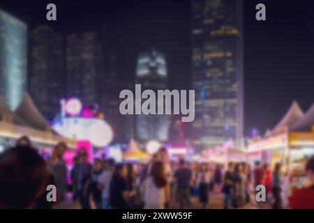 Scène nocturne floue d'un marché de rue de Hong Kong avec beaucoup de gens devant de grands bâtiments. Banque D'Images