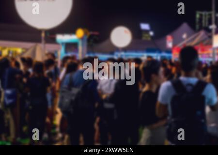 Une scène nocturne floue de personnes rassemblées à Hong Kong, en Chine. Le fond est rempli de lumières bokeh, créant une atmosphère festive. Banque D'Images