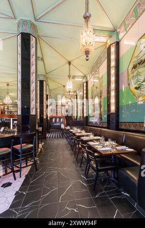 Vue en bas de l'allée des tables et de la banquette à côté du bar dans le restaurant art déco rénové Banque D'Images