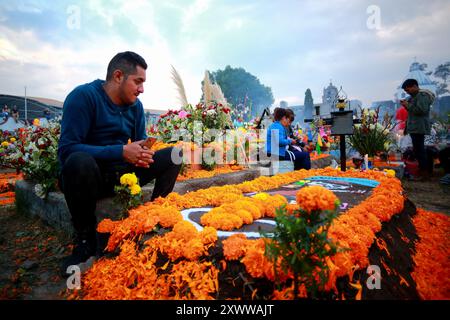 Ciudad de Mexico, Mexique - 2 novembre. 2023 : Man observe la tombe décorée de son parent dans le cimetière de Mixquic pendant le jour des morts Banque D'Images