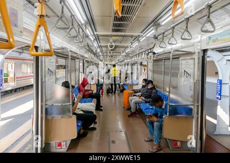 Jakarta, Indonésie - 18 août 2024 : vue à l'intérieur du train de banlieue Jakarta. Passagers assis dans un wagon de train. Banque D'Images