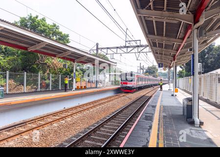 Jakarta, Indonésie - 18 août 2024 : un train de banlieue arrive à la gare et deux gardes de sécurité sont sur le quai. Banque D'Images