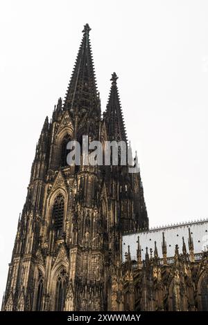 Les vues ascendantes capturent la maçonnerie des deux flèches gothiques et du tracery ajouré de la cathédrale de Cologne s'élevant contre le ciel, à Cologne, en Allemagne. Banque D'Images