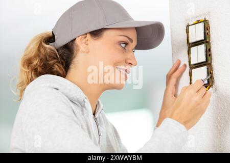 femme installant des interrupteurs électriques vérifiant la fixation des vis Banque D'Images