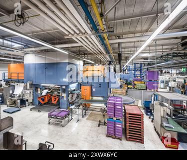 Vue intérieure d'une usine industrielle moderne en Allemagne, présentant des machines avancées et des conteneurs de stockage colorés. L'image met en valeur l'environnement organisé et high-tech d'une usine de fabrication contemporaine. Banque D'Images