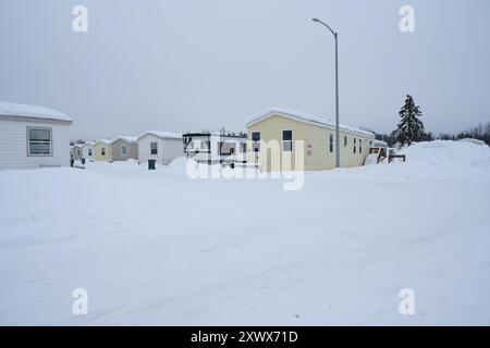 Une scène hivernale sereine avec un parc de caravanes enneigé à Anchorage, Alaska. L'image montre plusieurs remorques recouvertes de neige, illustrant le calme et l'isolement de l'hiver en Alaska. Banque D'Images