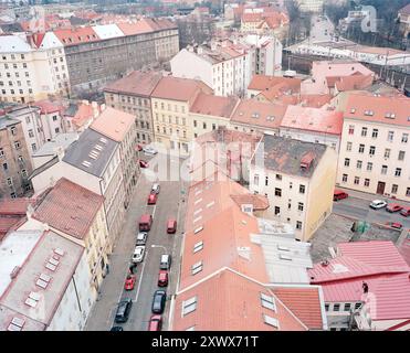 Une vue aérienne pittoresque de Prague présentant des bâtiments historiques colorés avec des toits rouges. L'image capture également une scène de rue dynamique, mettant en valeur l'architecture urbaine et le charme européen traditionnel. Banque D'Images