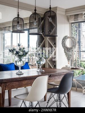 Suspensions au-dessus de la table avec des fleurs dans des vases en verre dans la salle à manger moderne élégante de l'appartement de Londres, Royaume-Uni Banque D'Images